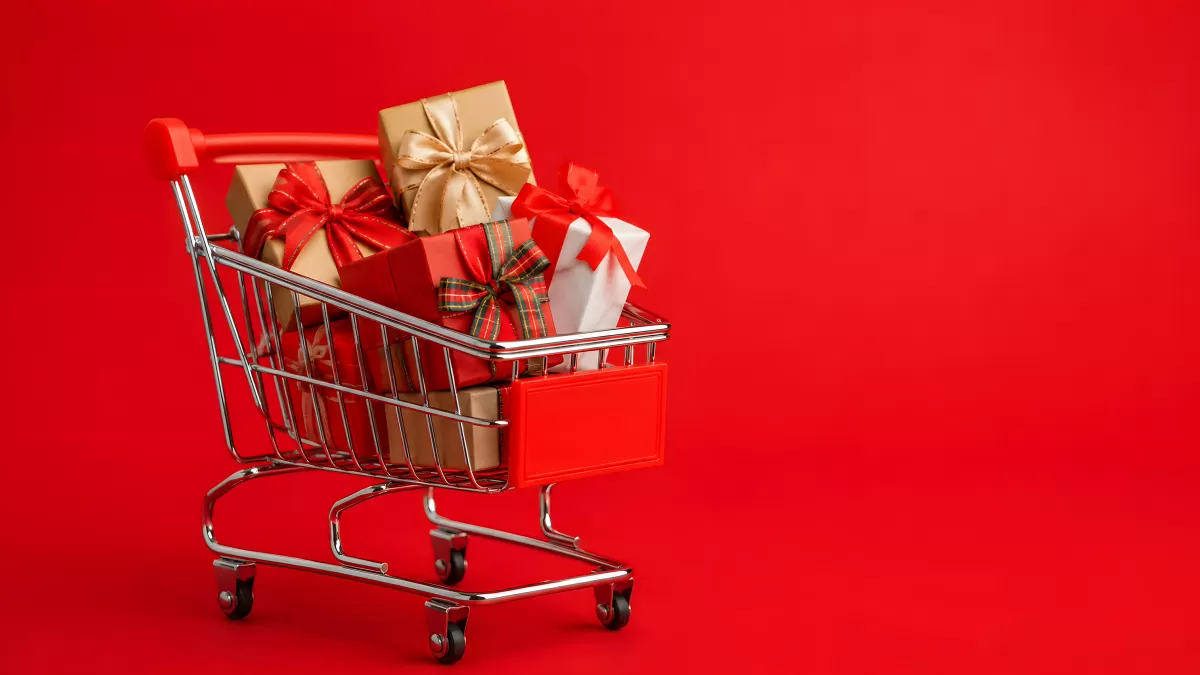 Einkaufswagen voller Weihnachtsgeschenke auf Rot