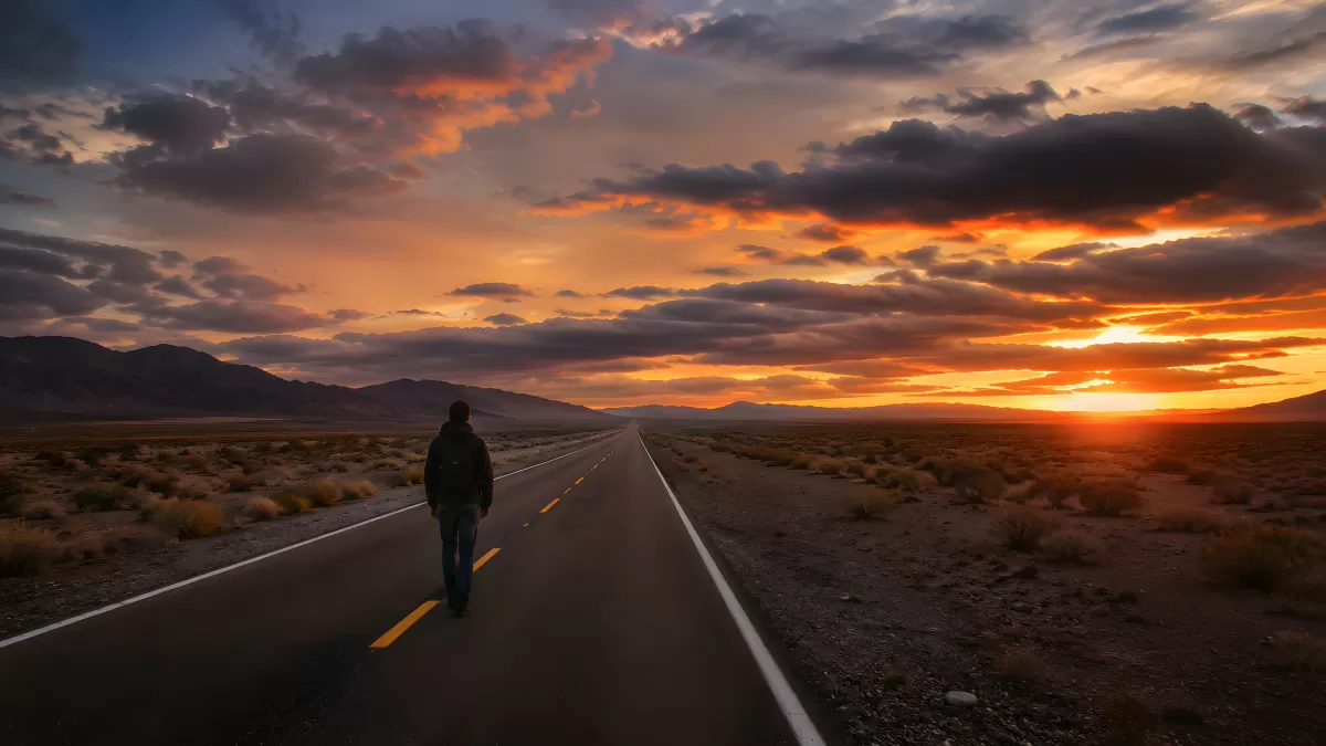 Einsamer Wanderer auf Wüstenstraße beim Sonnenuntergang