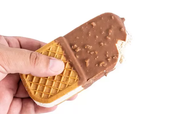Eiscream-Sandwich mit Waffel von einer Hand gehalten, vor weißem Hintergrund