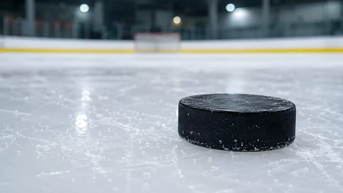 Eishockeypuck auf glänzender Eisfläche in der Halle