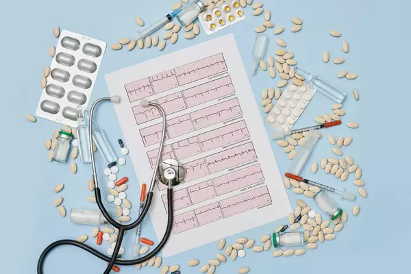 EKG cardiogram paper and pile of medical pills, medicines and stethoscope