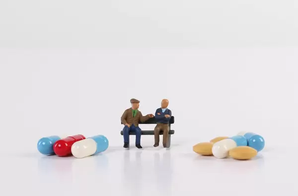 Elderly people sitting with pills on white background