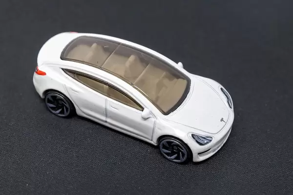 Electric car as a toy;: Hot Wheels Tesla Model 3 with glass roof, on dark surface