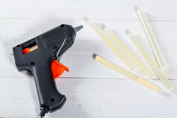 Electric glue gun on white wooden table
