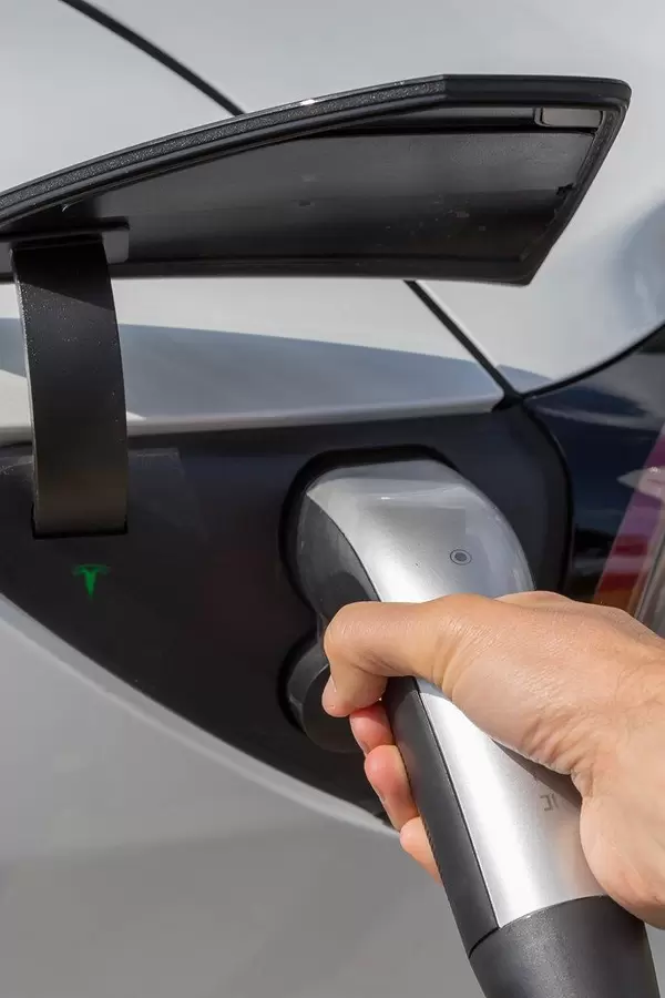 Electric vehicle: Man holding a type 2 connector during Tesla charging in Wilnsdorf, Germany