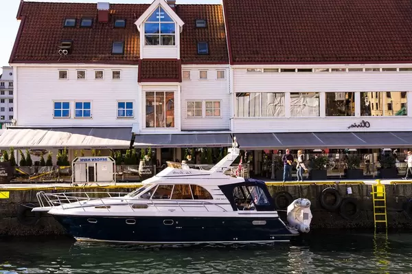 Elegant yacht in the harbor of Bergen, Norway with restaurant Olivia Zachariasbryggen behind (Flip 2019)