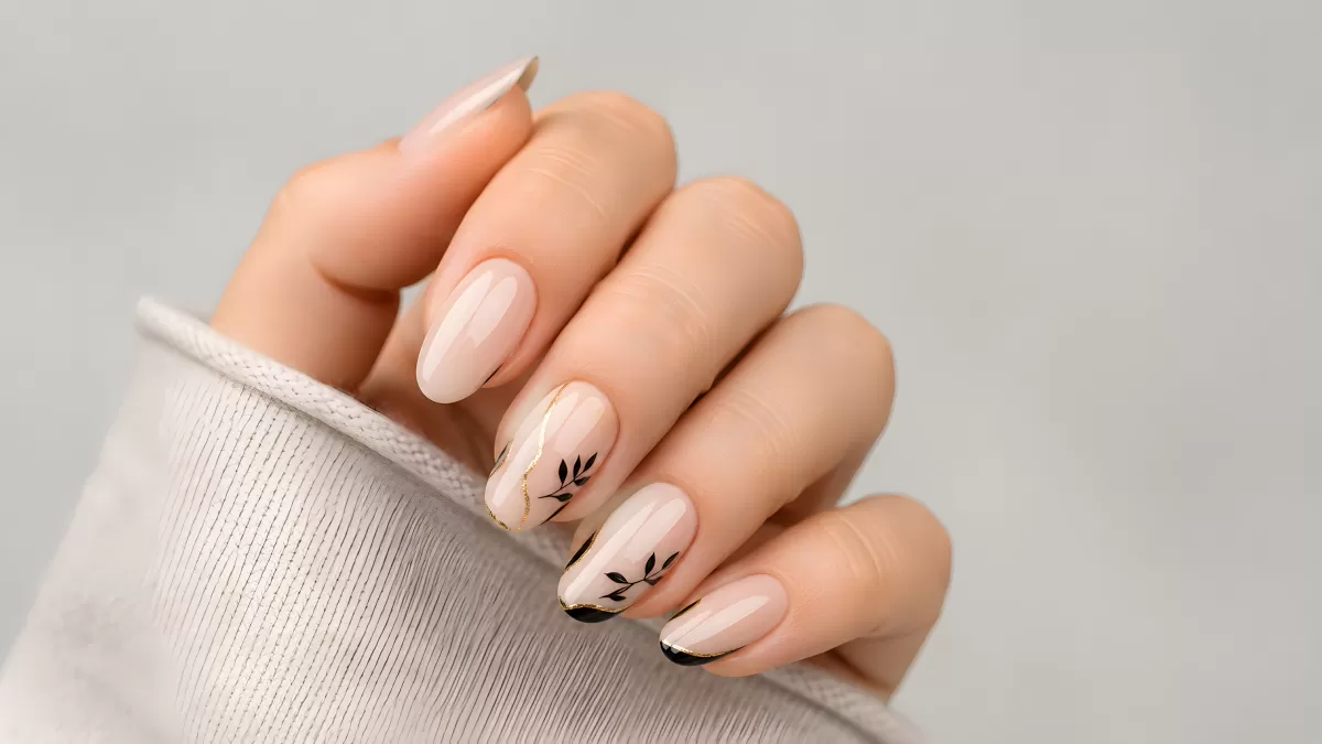 Elegante Nude-Nägel mit schwarzen Blattmotiven und Goldlinie