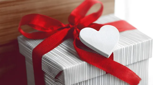 Elegantes Geschenkpaket mit roter Schleife und Herzanhänger