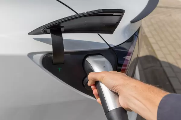 Elektrofahrzeug: Mann hält einen Typ-2 Stecker während der Tesla-Aufladung