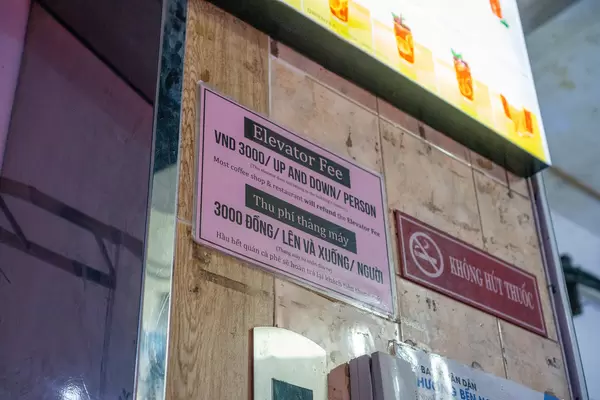 Elevator Fee Sign Board next to a No Smoking Sign inside The Cafe Apartment Building in Saigon, Vietnam