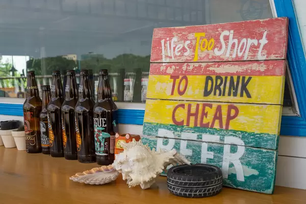 Empty Beer Bottles, Seashells and Wooden Board with Saying as Decoration at an Outdoor Bar Space in Saigon, Vietnam