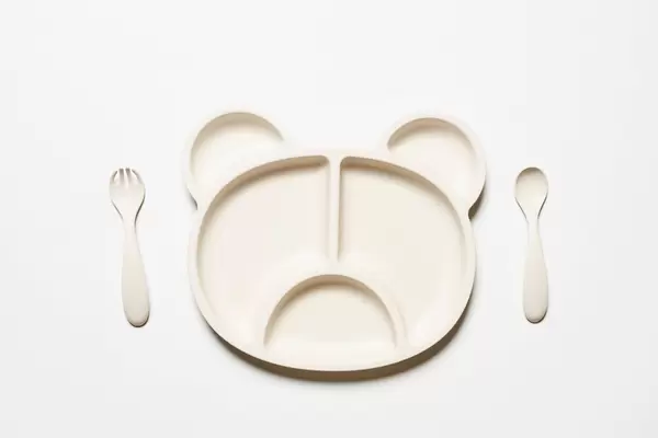 Empty eco-friendly bamboo plate in shape of bear and white spoon and fork