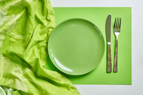 Empty green plate with spoon and fork