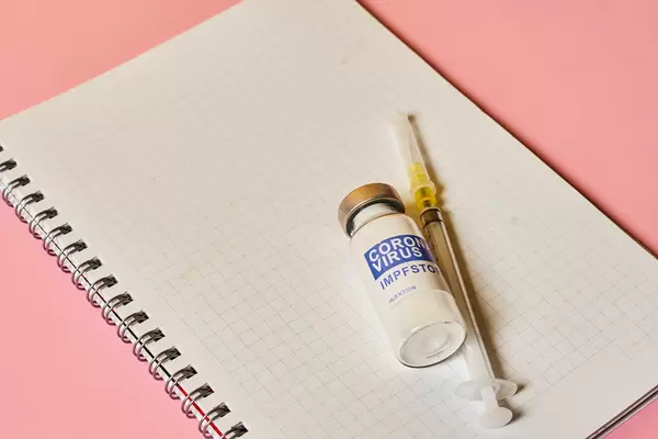 Empty notepad with covid-19 vaccine dose and syringe