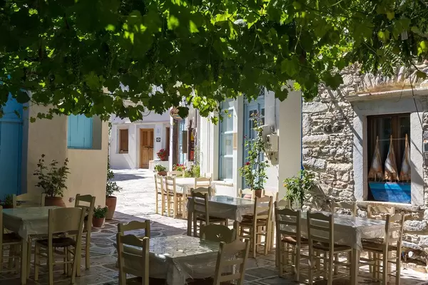 Empty restaurant tables in the shade on a quiet side street of Halki, picturesque tiny village on Naxos