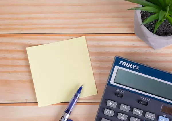 Empty sticky note with calculator on wooden tabel