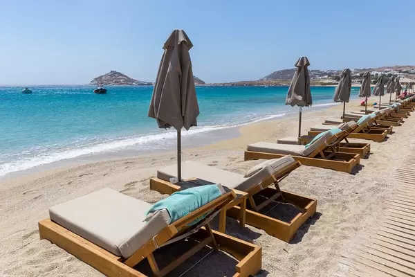 Empty sun beds and closed beach umbrellas. Holiday in summer 2020 at Kalafati beach, Mykonos