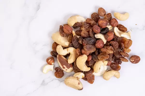 Energielieferant Nuss-Mix mit Haselnüssen, Cashews, brasilianischen Nüssen und Rosinen auf Marmortisch