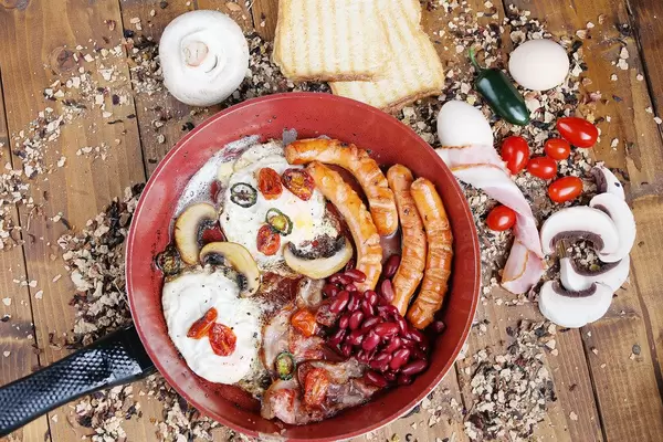 Englisches Frühstück in einer Bratpfanne auf Holzhintergrund