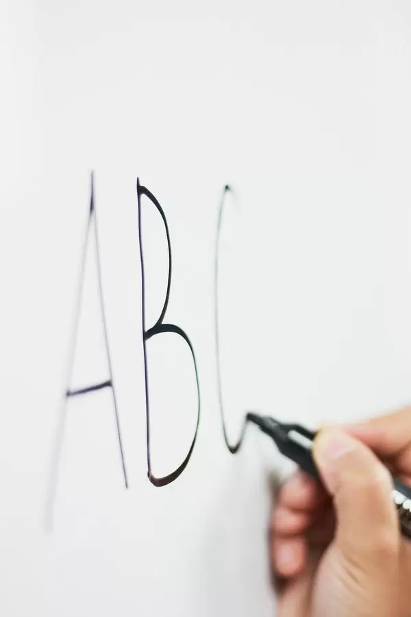 English for kids. First lesson. A teacher writing ABC on the whiteboard