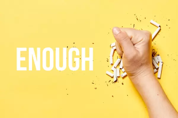 Enough. Stop smoking. Fist smudging pile of cigarettes