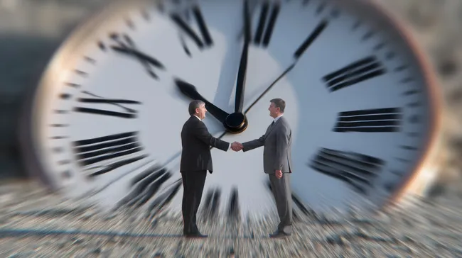 Erfolgreiches Geschäftsabkommen - Hände schütteln vor Uhr