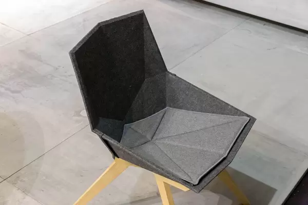 Ergonomisch geformter Stuhl mit Sitzfläche aus grauem Filz und Beinen aus Holz