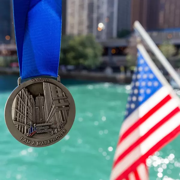 Erinnerung von dem Chicago Marathon am 13.10.2019: Medaille mit blauer Schleife und USA-Fahne und Fluss im Hintergrund