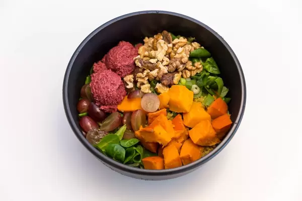 Erntedank Bowl with beetroot hummus, lamb's lettuce, warm curry quinoa, roasted Hokkiado pumpkin, red grapes, young leek, walnut kernels and yoghurt-orange dip