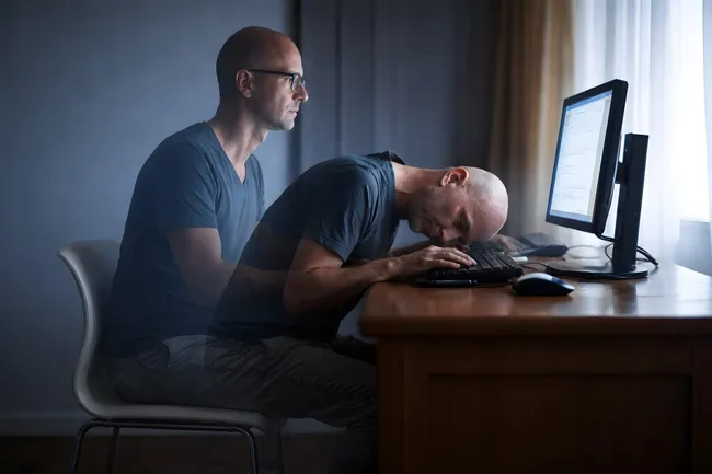 Erschöpfter Mann am Computer in dunkler Umgebung