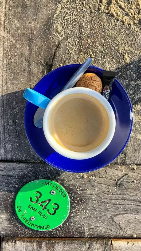 Espresso mit Amaretti und Portionenzucker auf Holztisch neben Plakette mit Tischnummer