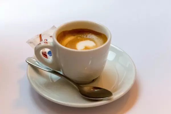 Espresso mit kräftiger Kaffeecrema in weißer Tasse mit Löffel und Zucker