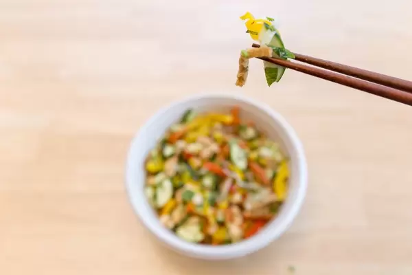 Essstäbchen mit einer Portion Gemüse über veganem Gericht aus Gemüse über Holztisch