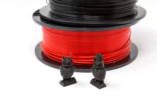 Eulen aus schwarzem Plastik vor PLA-Filament Spulen
