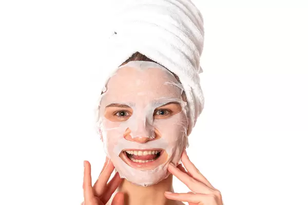 Face of smiling girl with cosmetic cloth mask