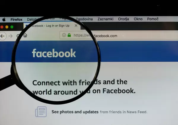 Facebook-Logo am PC-Monitor, durch eine Lupe fotografiert