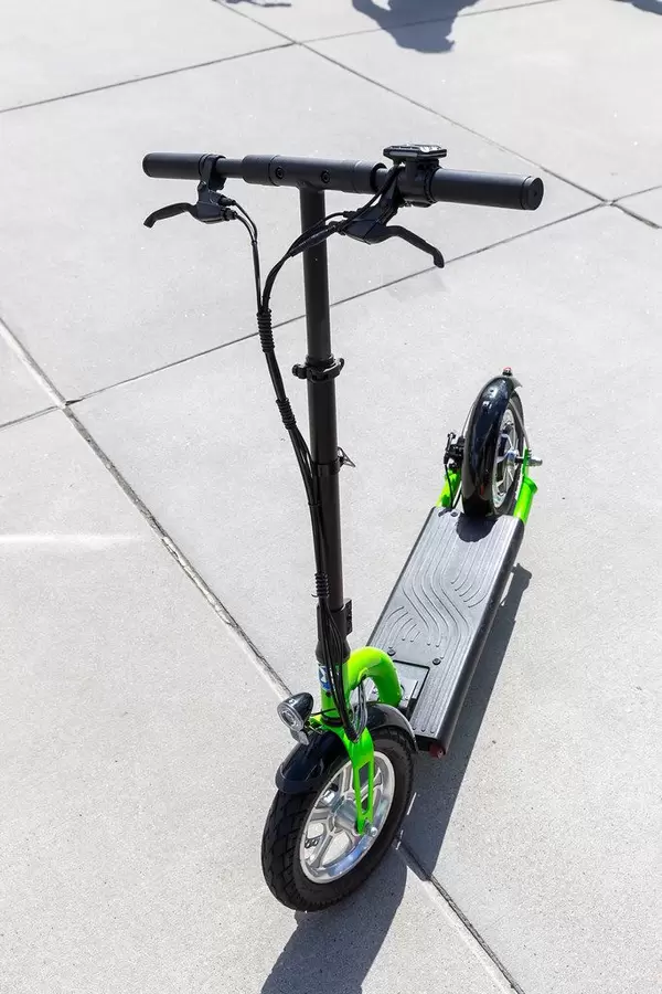 Fahrbereiter elektrischer Tretroller in grün und schwarz, als umweltschonendes Fortbewegungsmittel für Stadtfahrten