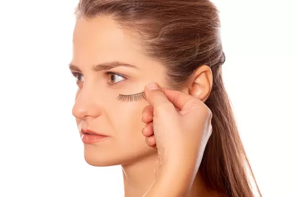 False eyelashes in hand near the girl's face