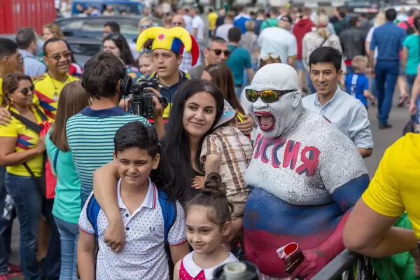 Familie fotografiert sich mit einem über den ganzen Körper bemalten russischen Fußball-Fan