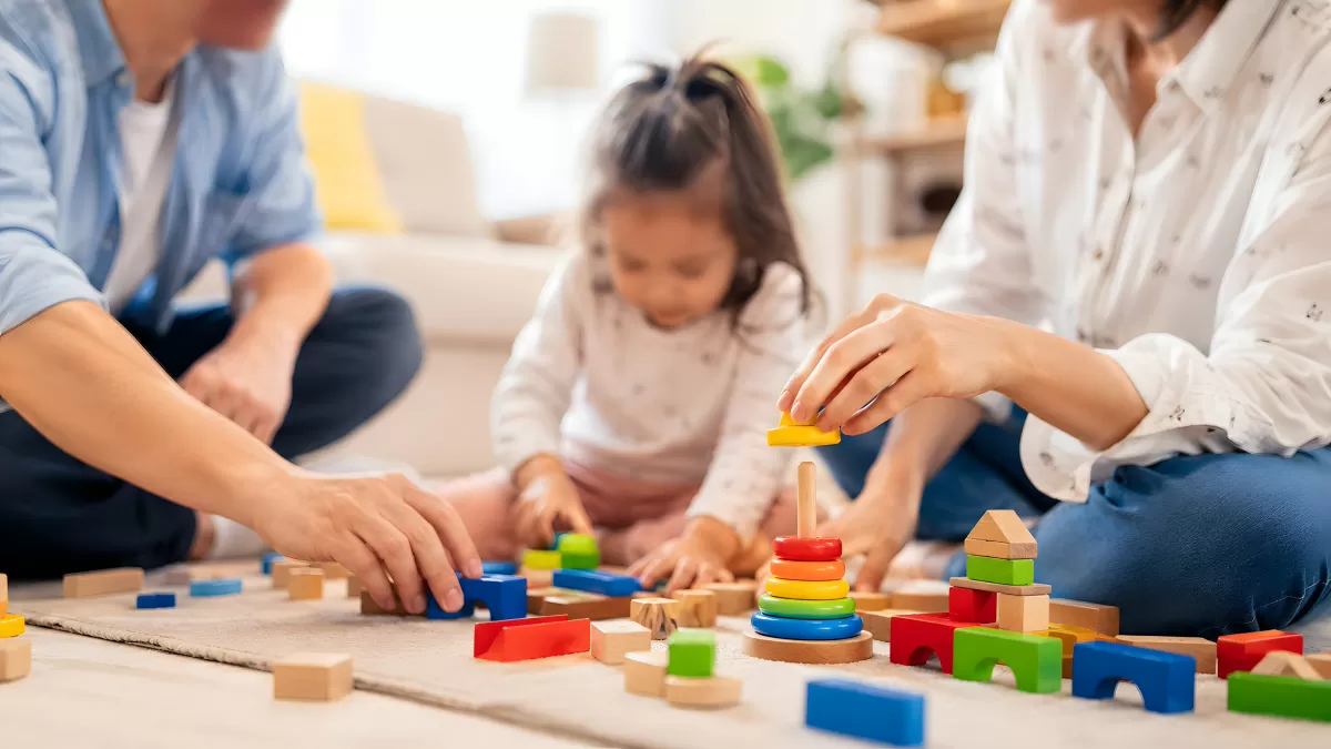 Familie spielt gemeinsam mit Holzbausteine auf dem Boden