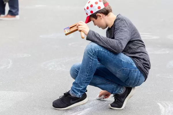 Fan mit gepunkteter Mütze (Bergwertung) malt mit Kreide auf der Straße