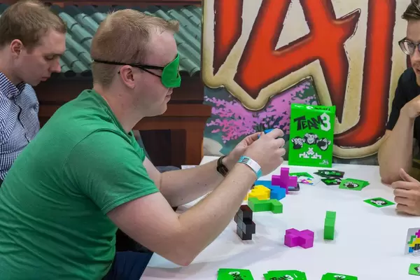 Fans spielen Team 3 - Mann hat die Augenbinde auf und fühlt ein Baustein