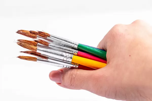 Farbpinsel in einer Frauenhand vor weißem Hintergrund