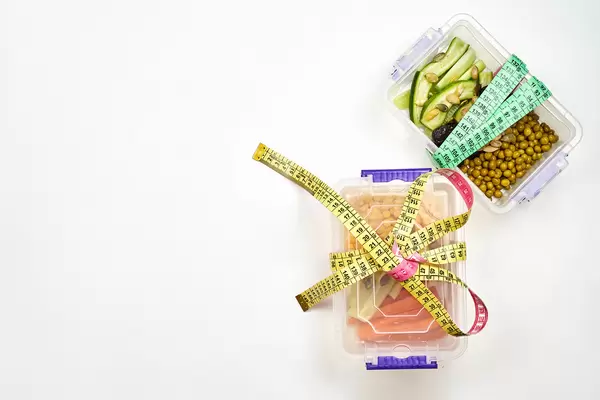 Fat burning food packed in plastic containers and tied with measuring tapes