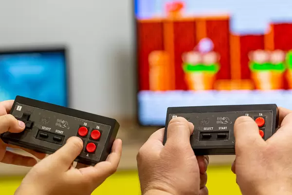 Father and son hands with joysticks play an eight-bit game