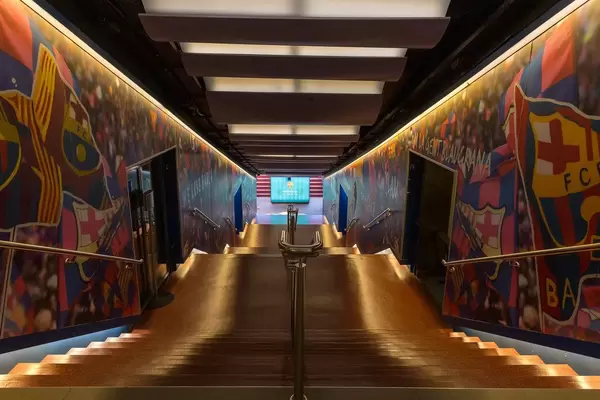 FC Barcelona players' tunnel leads to Camp Nou Stadium with painted club flags on the walls and illuminated stairway in Spain