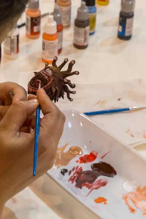 Feine Handarbeit mit Vallejo Acrylfarben: Eine Frau bemalt eine Spielfigur sehr detailiert