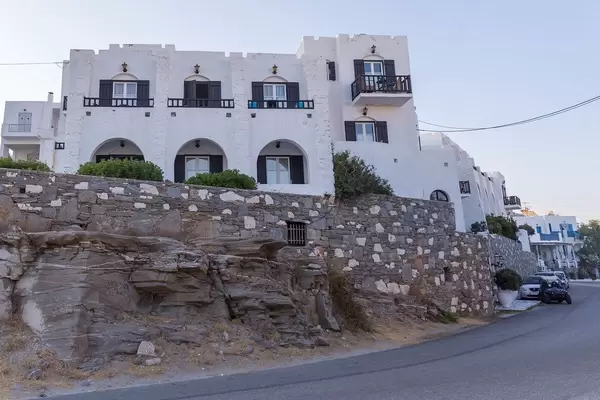 Felsen und Mauer vor einem griechischen Wohnhaus aus weißem Kalkstein, auf der Mittemeerinsel Paros