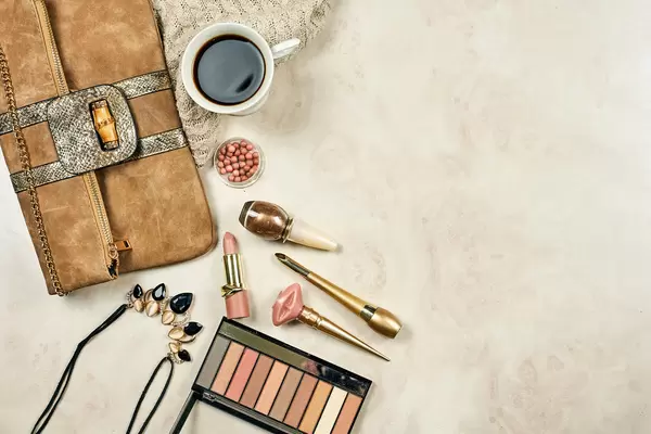 Female bag, different feminine cosmetics tools and cup of coffee