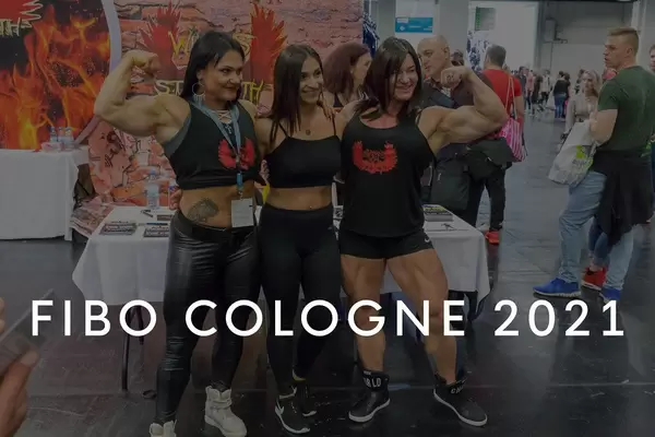 Female bodybuilder with Wings of Strength shirts show their muscles, with the picture title "Fibo Cologne 2021"